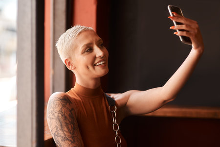 Take a selfie and be happy. an attractive young woman taking a selfie in a cafe.の写真素材