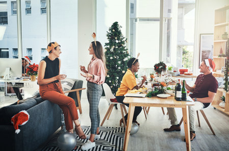 Its chit chat time. Full length shot of a group of cheerful young people having chats with each other while celebrating Christmas together at home.の写真素材
