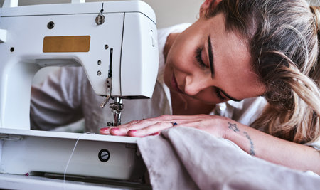 Adventure begins when you enter your sewing room. a young fashion designer using a sewing machine in her workshop.の写真素材