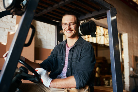 Only a select few can drive these pair of wheels. a young male warehouse worker driving a forklift.