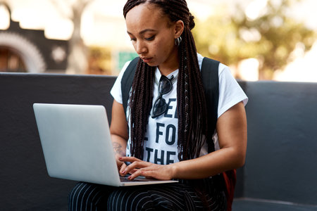 Blogging is a lifestyle. an attractive young woman using a laptop while relaxing outdoors.の写真素材
