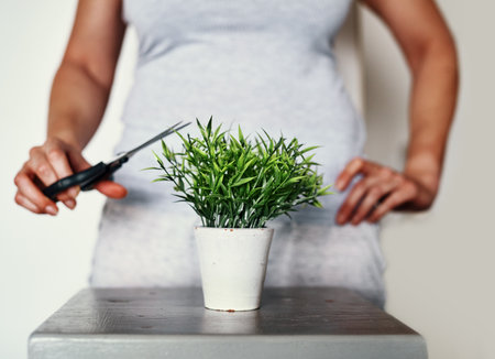 A little trimming is required every now and then...an unrecognizable woman using a pair of scissors to trim a pot plant at home.の写真素材