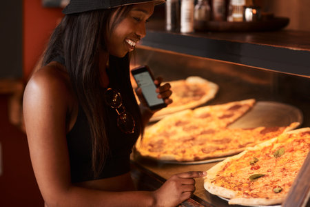 I just cant decide which one I want. a young woman ordering pizza at a cafe.の写真素材