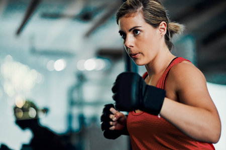 Dynamite comes in small packages. an attractive young female kickboxer working out in the gym.