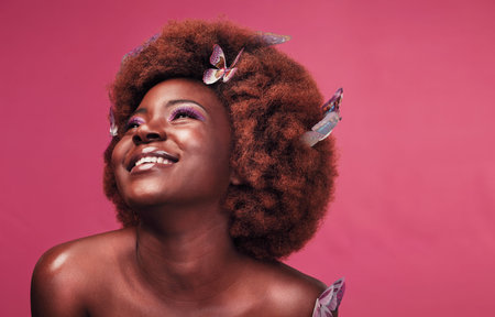 I just love everything about butterflies. Studio shot of a beautiful young woman smiling while posing with butterflies in her hair against a purple background.の写真素材