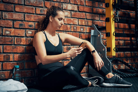 This app helps me to keep track of my workouts. a sporty young woman using her cellphone during her...