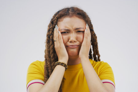 What am I going to do. Studio shot of a young woman crying while standing against a gray background.の写真素材