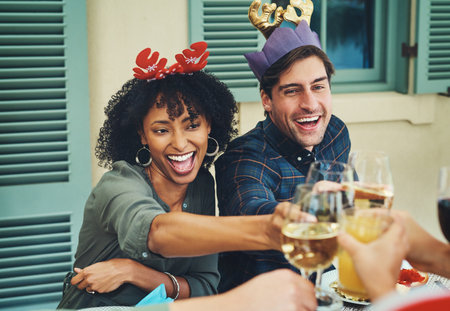 Let the good times roll. a beautiful young couple joining their glasses for a toast at a Christmas lunch party.の写真素材