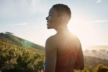 Happy black woman, fitness and thinking in nature, mountains and sunshine flare for motivation, happiness and positive mindset. Female athlete, smile and mindfulness with vision, wellness and energyの写真素材