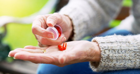I hate it but its important. an unrecognizable elderly woman about to take medication outside in a...