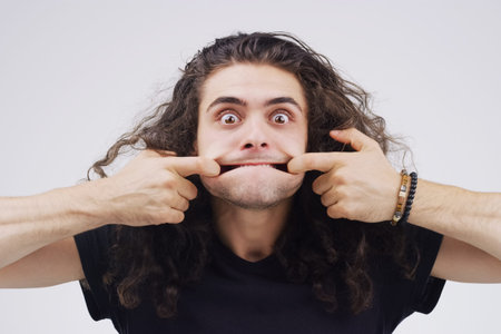 Keep life lighthearted. Studio shot of a young man making a funny face against a gray background.