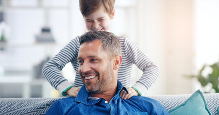 Hopefully that will remove some tension off me. a cheerful father and son relaxing on a couch and spending some time together indoors.の写真素材