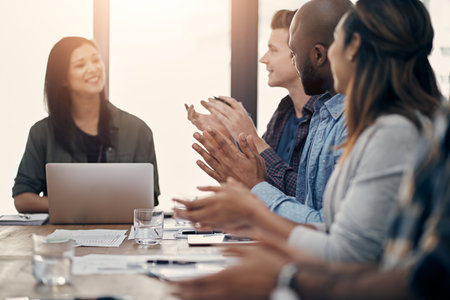 Good news deserves a round of applause. a group of young businesspeople clapping during a meeting in a modern office.の写真素材