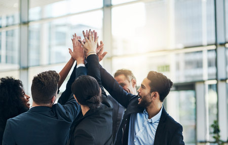 Lets raise the bar. a group of businesspeople forming a huddle with their hands at work.