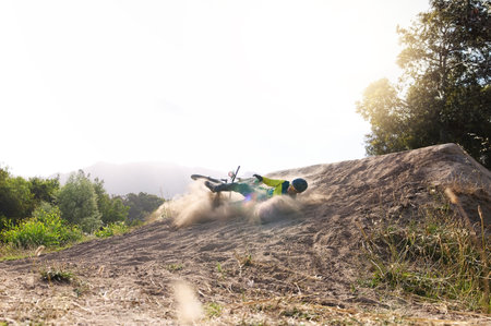Cycling, fall and extreme sports, accident and dirt bike dust and rider for sports workout in nature for fitness and lifestyle. Bicycle, cyclist and injury with sports, biking or nature adventureの写真素材