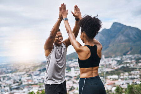 We made a new record. a sporty young couple high fiving each other while exercising outdoors.の写真素材