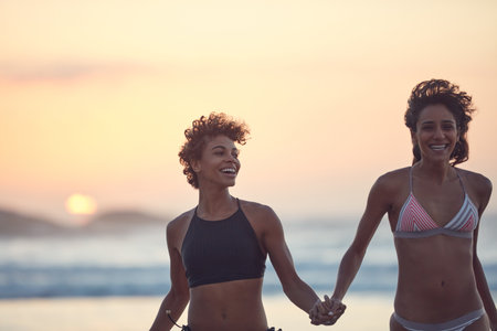 The beach is where we have the most fun. two young women enjoying themselves at the beach.の写真素材