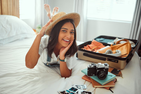 Travel, luggage and woman on bed with clothes, camera and suitcase for adventure, holiday and vacation. Traveling lifestyle, freedom and portrait of girl in bedroom pack for journey, tourism and tripの写真素材