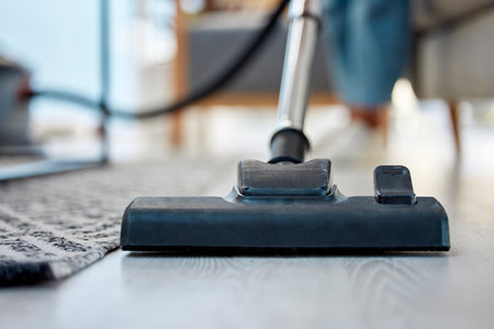 Vacuum cleaner, floor closeup and home living room for hygiene, spring cleaning and dust by blurred background. Cleaning, dirt and flooring with vacuum appliance, carpet and wood in apartment in Romeの写真素材