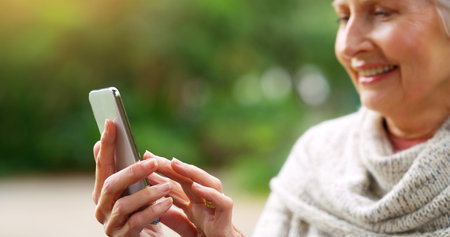 I need my reading glasses. a cheerful elderly woman texting on her cellphone while being seated on a...