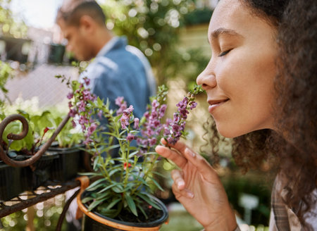 Smelling, plants and face of a woman at a nursery, flower shopping and aroma at a garden market. Happy, peace and girl with smell of flowers, pot plant and floral heather ecology at a gardening shopの写真素材
