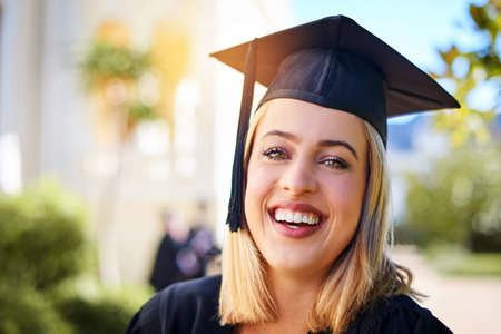 Its worth it at the end. a happy young woman standing outside on graduation day.