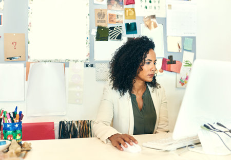 You can do a lot with the click of a button. a designer working on her computer in her office.の写真素材