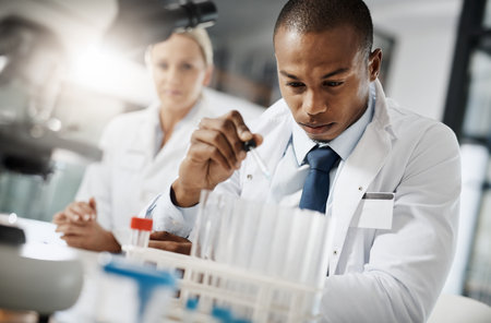 All in the name of medicine. a handsome young male scientist testing a sample while doing research in his lab.の写真素材