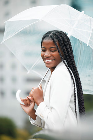 Stylish, trendy woman with an umbrella in the city for insurance on a cold winter day. Rain, weather and elegant female with style covering herself in an urban town in a fashionable jacketの写真素材
