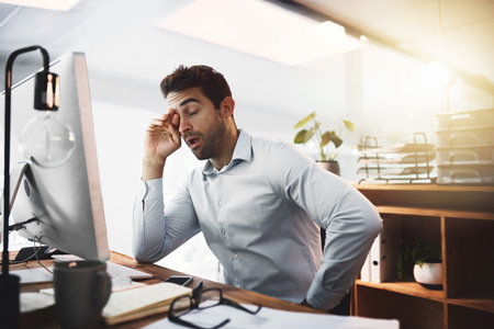 How much longer do I need to be here. a young businessman looking exhausted while working late on a...