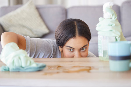 Focus, table or woman cleaning furniture surfaces with product for messy or dirty bacteria in house...