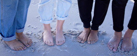 Beach feet, friends and people on vacation, holiday or summer trip. Toes, freedom and group of men and women standing on sandy seashore, seaside or coast, having fun or enjoying quality time outdoorsの写真素材