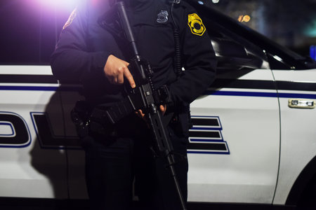 Hes packing some serious heat. an unrecognizable policeman standing with his assault rifle while out...