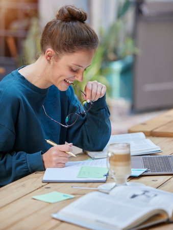 Woman, laptop and notebook writing in cafe, coffee shop or restaurant for university, college or...