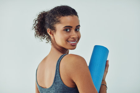 Time to start my yoga session. Studio shot of an attractive young woman getting ready to practice yoga against a grey background.の写真素材