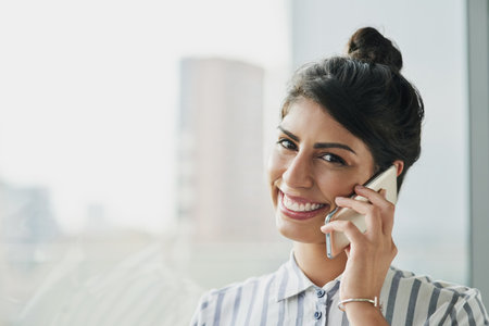 To stay successful, you need to stay connected. Portrait of a confident young businesswoman talking on a cellphone in an office.の写真素材