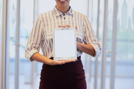 Online is the best place to advertise. Closeup shot of an unrecognizable businesswoman holding up a digital tablet with a blank screen in an office.の写真素材