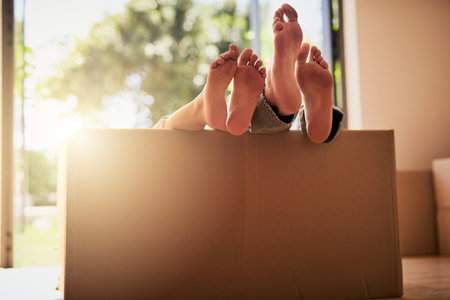 Taking a break from all the moving. an unidentifiable couple lying in a box together with their feet sticking out.の写真素材