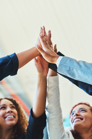 The determined team always goes further. a group of businesspeople high fiving together in an...
