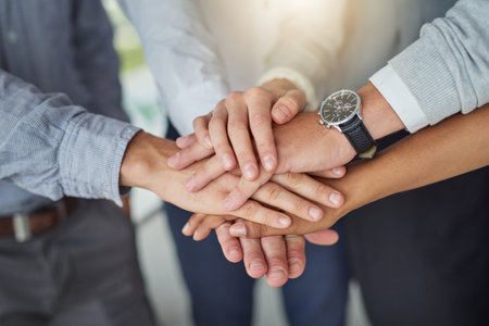 Gather the team and get things done. a group of colleagues joining hands in solidarity in a modern...