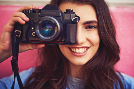Cameras are handy to capture memories. Portrait of a beautiful young woman holding a dslr camera and...