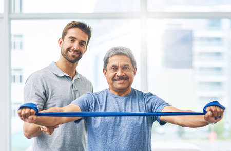 Im getting better one stretch at a time. Cropped portrait of a young male physiotherapist assisting a senior patient in recovery.の写真素材