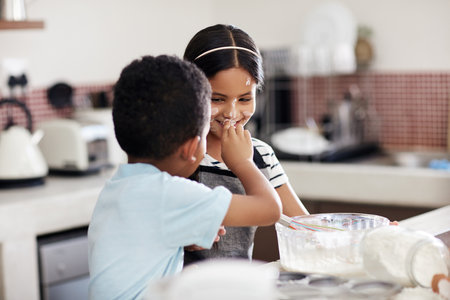 Being silly with my sibling. an adorable brother and sister baking together in the kitchen at home.の写真素材