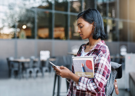 Shes got her class schedule on her cellphone. an attractive young female student using her cellphone...