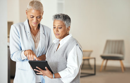 Senior women, tablet and working in business office for web collaboration, digital marketing strategy or planning online networking. Businesswomen, partnership conversation and digital tech deviceの写真素材
