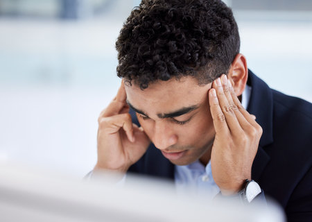 Stress headache, burnout and man in office overwhelmed with workload at computer. Mental health, frustrated and overworked tired trader at startup, anxiety from deadline time in stock market crisis.の写真素材