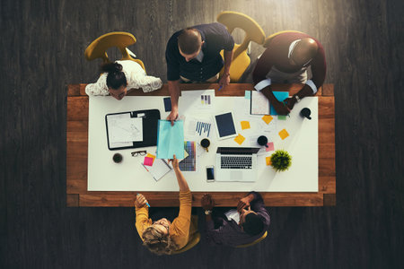 Collaborating their way to increased productivity. High angle shot of a group of businesspeople having a meeting in a modern office.の写真素材