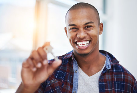 The keys to home ownership. a handsome young man holding house keys in his new home.の写真素材