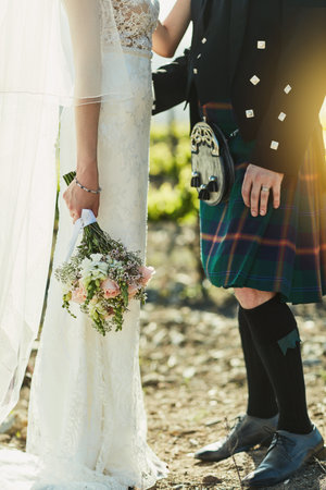 How traditional. an unrecognizable bride and groom holding each other while standing outside next to vineyards during the day.の写真素材