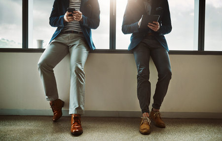 Business in the era of the app. two businessmen using a digital tablet and cellphone while leaning...